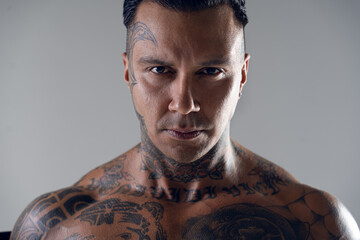 portrait of a handsome man with a tattoo on his face. Brutal handsome guy looking at us . Dangerous, hot, model. stern look 