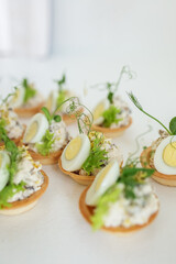 Close-up of tartlet with quail egg, cheese and chicken and microgreens. Food delivery and catering