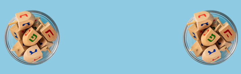 Jewish holiday Hanukkah concept. Wooden dreidel (spinning top) on blue background. Banner.