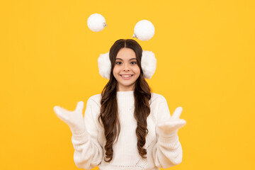Merry christmas and happy New year. Portrait of happy teenager child wears sweater and knitted gloves on yellow isolated background. Kid in winter clothes. Teen girl with decorative snow ball.
