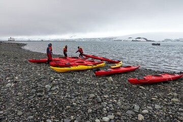 Travelers setting kayaks ready on the rocky shoreline of Yankee harbor in Antarctica
