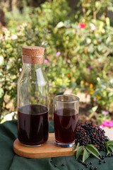 Elderberry drink and Sambucus berries on table outdoors