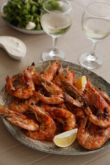 Plate of delicious cooked shrimps served with lemon and wine at table