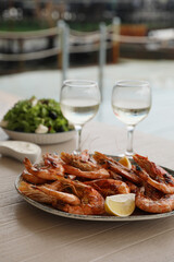 Plate of delicious cooked shrimps served with lemon and wine at table outdoors