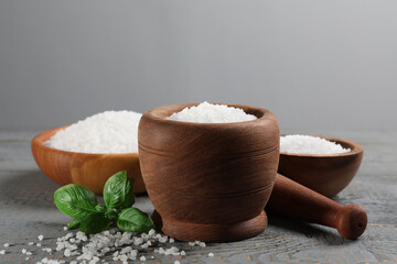 Pestle and mortar with natural sea salt on grey wooden table