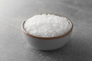 Bowl of natural sea salt on grey table