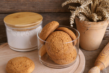 Cookies, flour and wheat spikes on wooden table