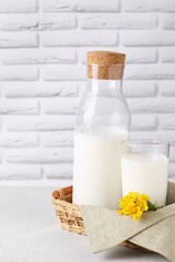 Glass and bottle of fresh milk on table against white brick wall