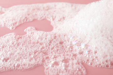 Fluffy bath foam on pink background, closeup