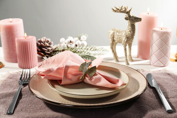 Stylish table setting with pink fabric napkin, beautiful decorative ring and festive decor on white...