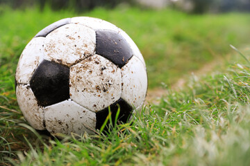 Dirty soccer ball on green grass outdoors, closeup. Space for text
