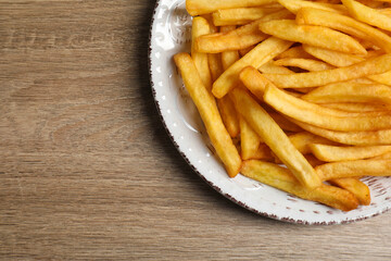 Tasty french fries on wooden table, top view. Space for text