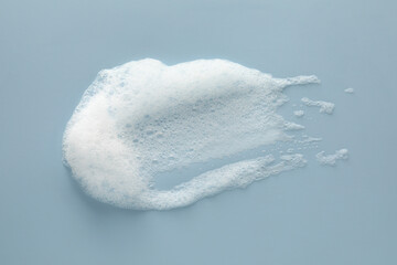 Smudge of white washing foam on color background, top view