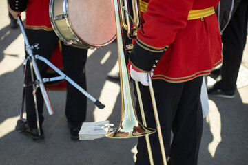 Orchestra member holds brass pipe. Trumpeter details. Ceremonial red uniform.