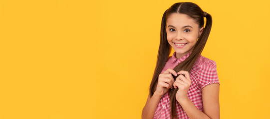 Beautiful girl child with timid smile touch hair yellow background. Child face, horizontal poster,...