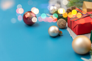 Christmas spruce with ball, gift and blurred shiny lights. Christmas or New Year Holiday atmosphere.