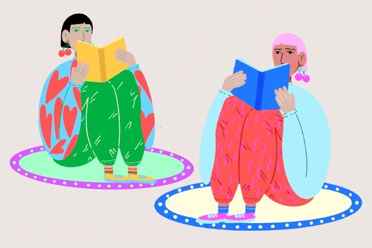 women one with black hair and one with pink hair sitting on the floor reading