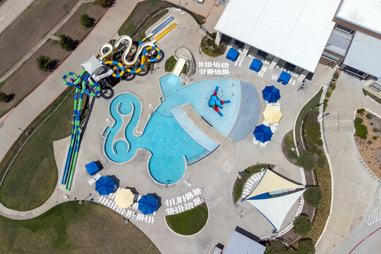Aerial view from flying drone of aquapark, water park with various water slides, pool, sun loungers and green area.