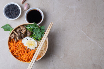 Noodle soup, ramen in a white bowl (bowl) with chicken egg, carrots, mushrooms on a light stone background.