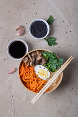 Noodle soup, ramen in a white bowl (bowl) with chicken egg, carrots, mushrooms on a light stone background.