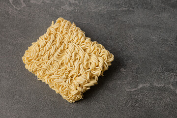 Square dry egg noodles in a briquette on a gray stone marble (slate) background.