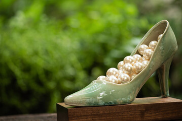 Old green ceramic shoe and pearl on nature background.