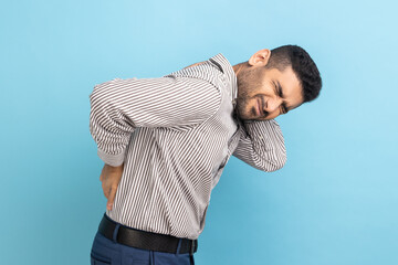 Backache or spine or kidney pain. Portrait of young sick businessman standing and touching his back...