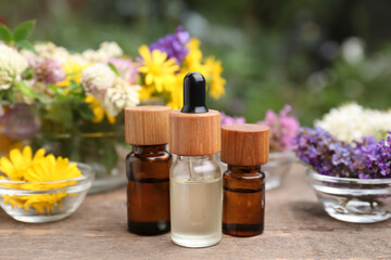 Fototapeta na wymiar Bottles of essential oils and many beautiful flowers on wooden table