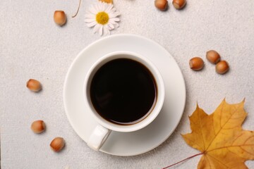 Flat lay composition with cup of hot drink and autumn leaves on light grey textured table