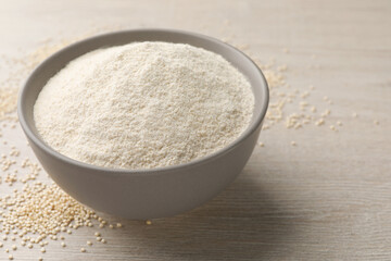 Ceramic bowl with quinoa flour and seeds on wooden table. Space for text