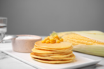 Tasty corn pancakes with sauce served on white marble table