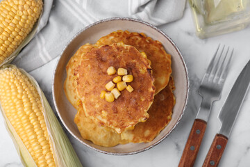 Tasty corn pancakes served on white marble table, flat lay