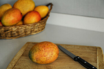 Tasty mango and knife on wooden board indoors