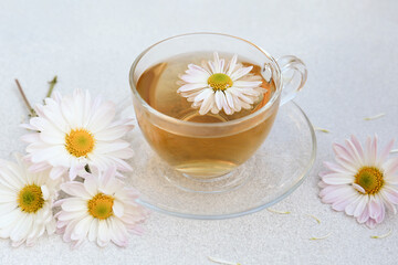 Fototapeta na wymiar Glass cup of delicious chamomile tea on white table