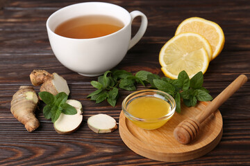 Bowl with honey for tea, lemon, mint and ginger on wooden table