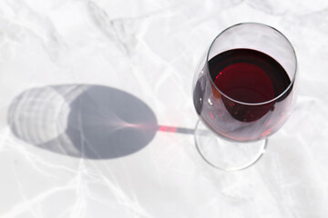 Glass of red wine served on white marble table, above view. Space for text