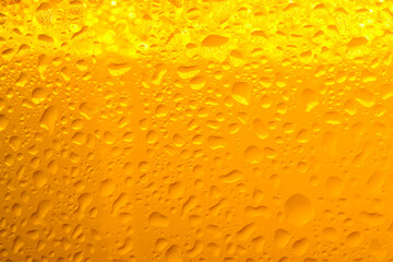 Glass of tasty cold beer with condensation drops as background, closeup