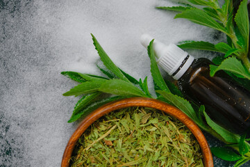 Stevia rebaudiana.Dry stevia, powder and liquid stevia extract in a bottle on a dark green...