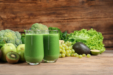 Glasses of fresh green smoothie and ingredients on wooden table, space for text