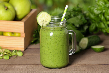 Mason jar of fresh green smoothie and ingredients on wooden table outdoors