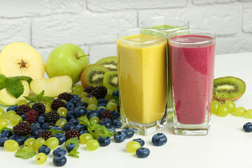 Fresh colorful fruit smoothies and ingredients on white table