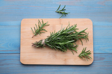 Bunch of fresh rosemary on light blue wooden table, top view