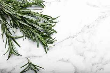 Sprigs of rosemary on white marble table, flat lay. Space for text