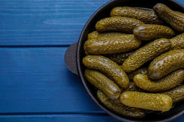Serving pan with pickled cucumbers on blue wooden table, top view. Space for text