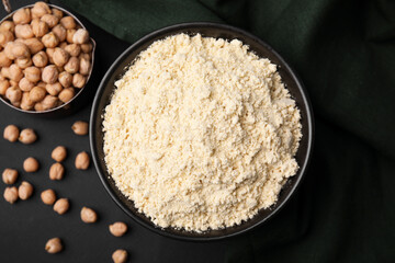 Chickpea flour in bowl and seeds on black table, flat lay