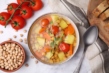 Flat lay composition of tasty chickpea soup in bowl and ingredients on white marble table