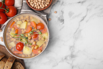 Tasty chickpea soup in bowl and ingredients served on white marble table, flat lay. Space for text