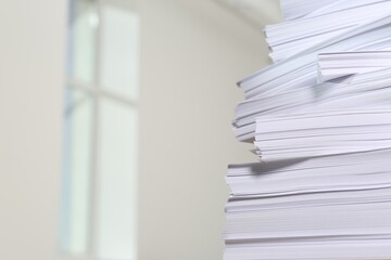 Stack of paper sheets against blurred background, closeup. Space for text