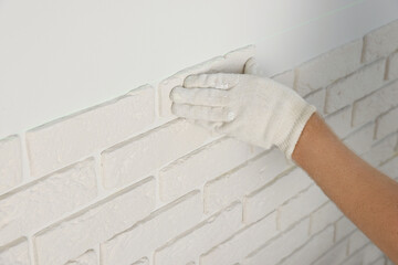 Worker installing decorative wall tiles in room, closeup