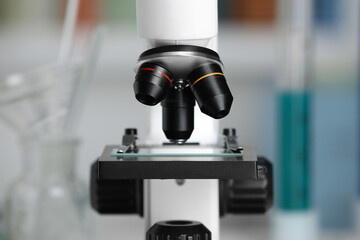 Modern medical microscope with glass slide on blurred background, closeup